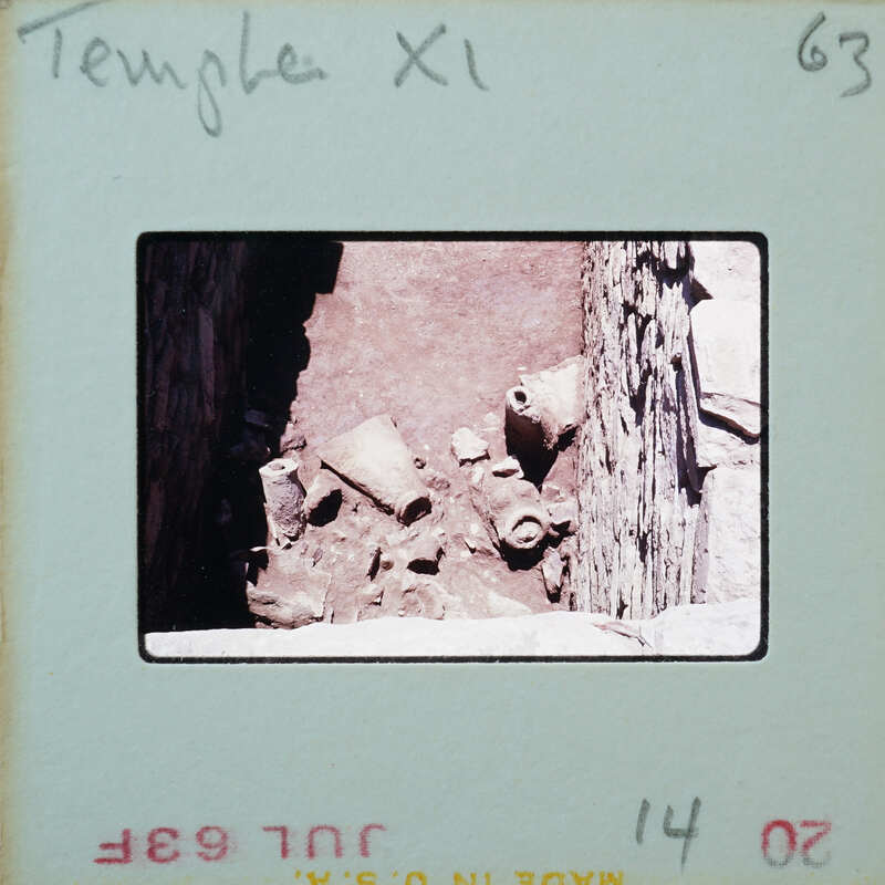 Stone walls around floor with broken pots.