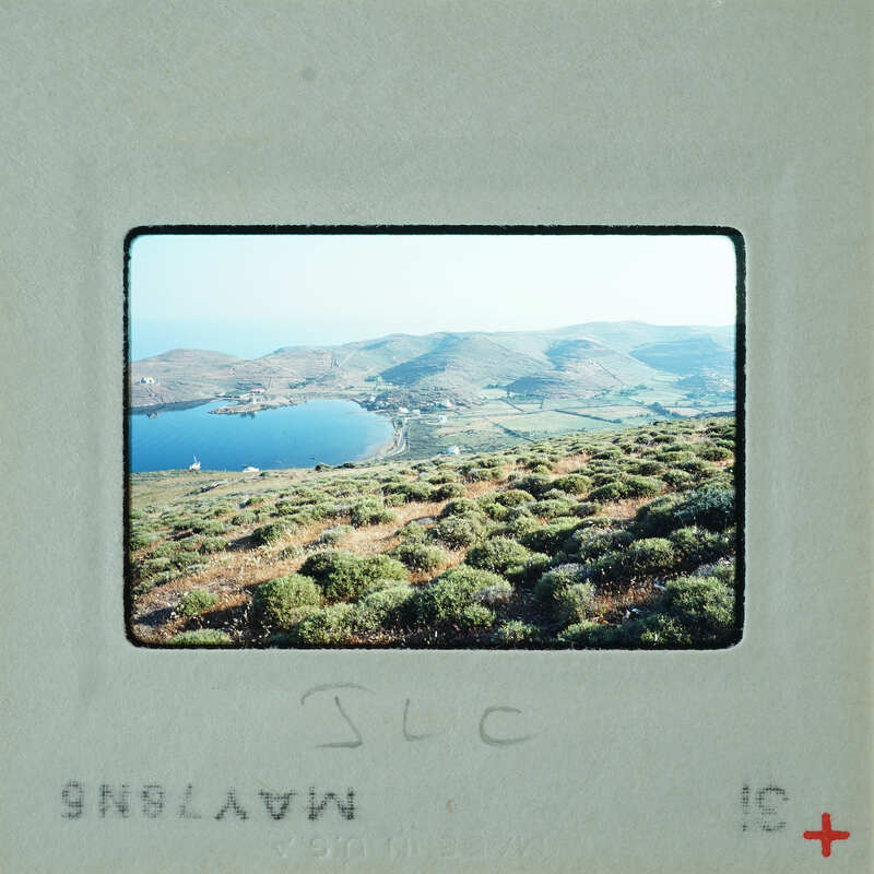 A vintage photograph of a scenic landscape with mountains, a lake, and greenery.
