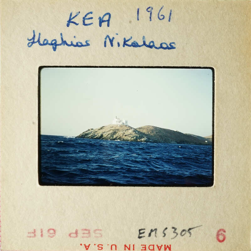 A photograph of an island with a lighthouse, taken from the water.