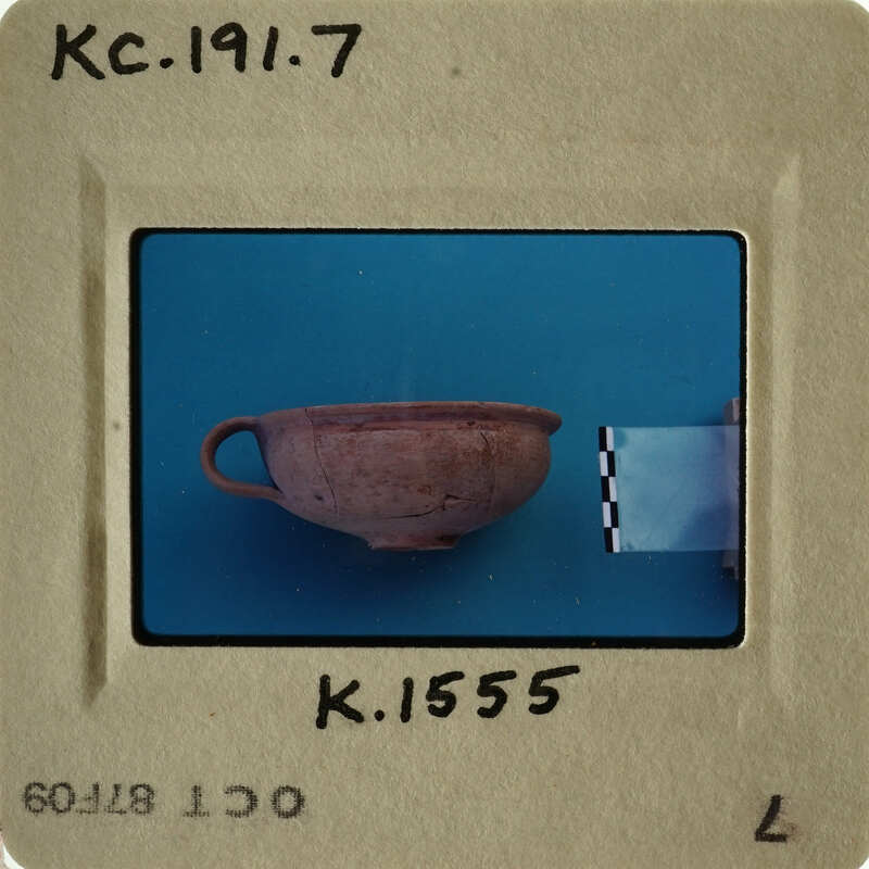 A small, weathered clay pot with handles on a blue background.