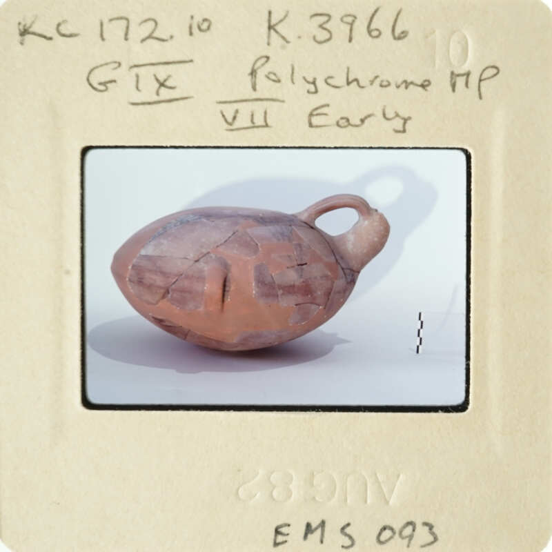 Ancient clay pot with face-like markings on display.