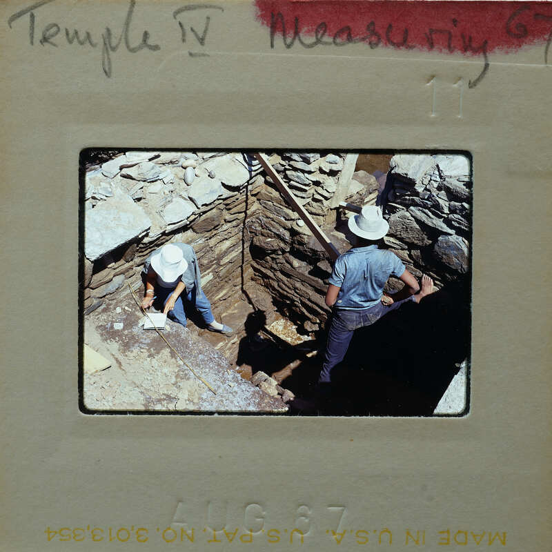 Two people working on a stone structure, restoring it.