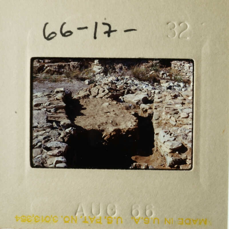 The photo shows an ancient stone structure, possibly ruins, with a dirt path leading up to it.