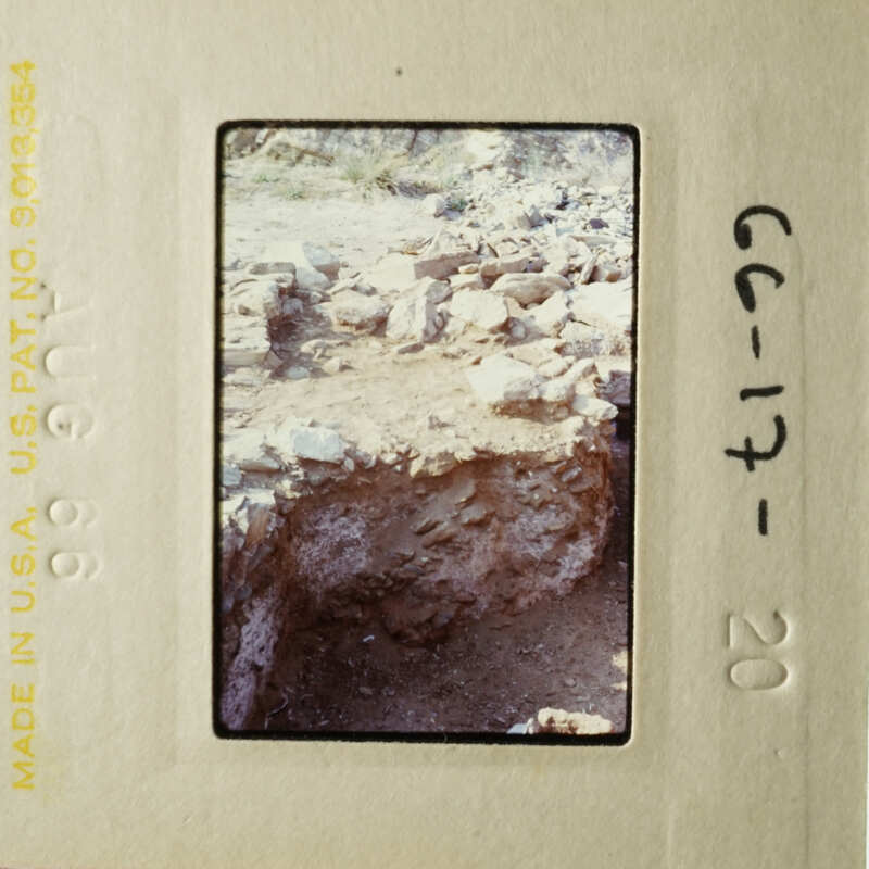 This is an image of a slide showing an archeological site with stone ruins and rubble, taken from a low angle.