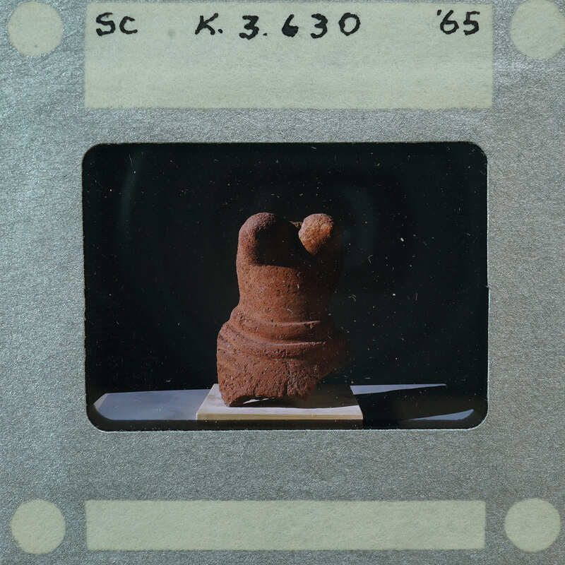 A photograph of a clay figurine with a dark background.