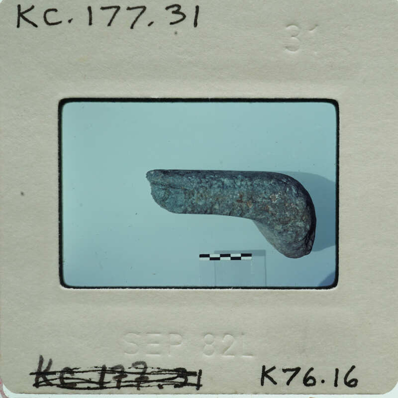 A small, dark gray rock on a white surface with a black border.