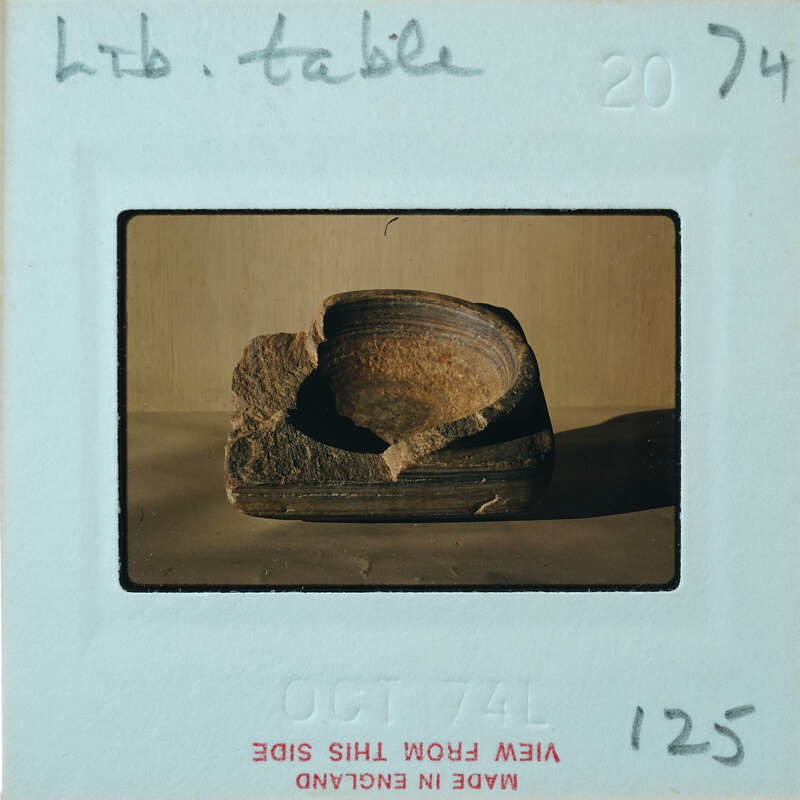 Fragment of squared off stone with rim and circular impression on top, from the top.