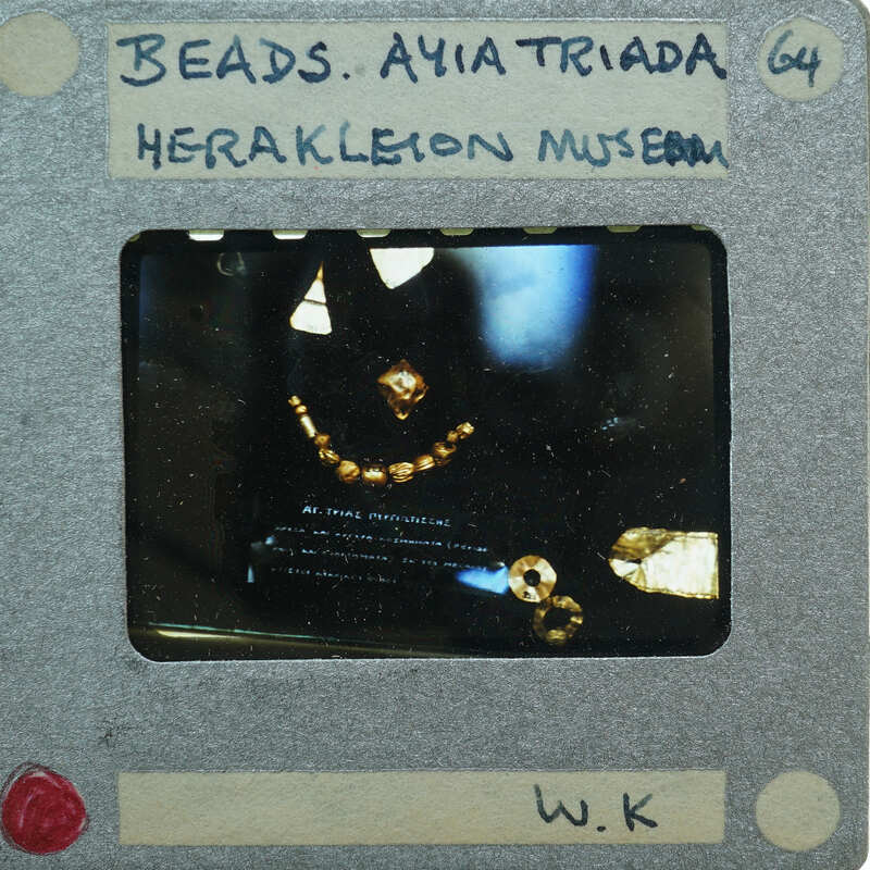 A photograph of a museum display case containing ancient jewelry and artifacts, with labels indicating their origin from the Heraklion Museum.