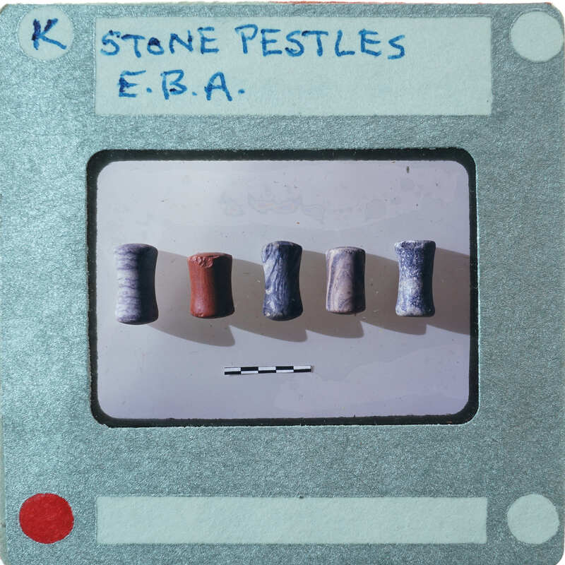 Five cylindrical stone pestles of various colors.