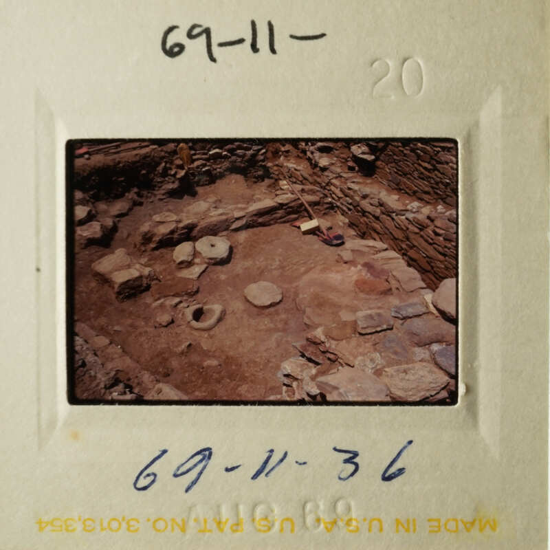 The photo shows an archaeological site with stone ruins and artifacts.