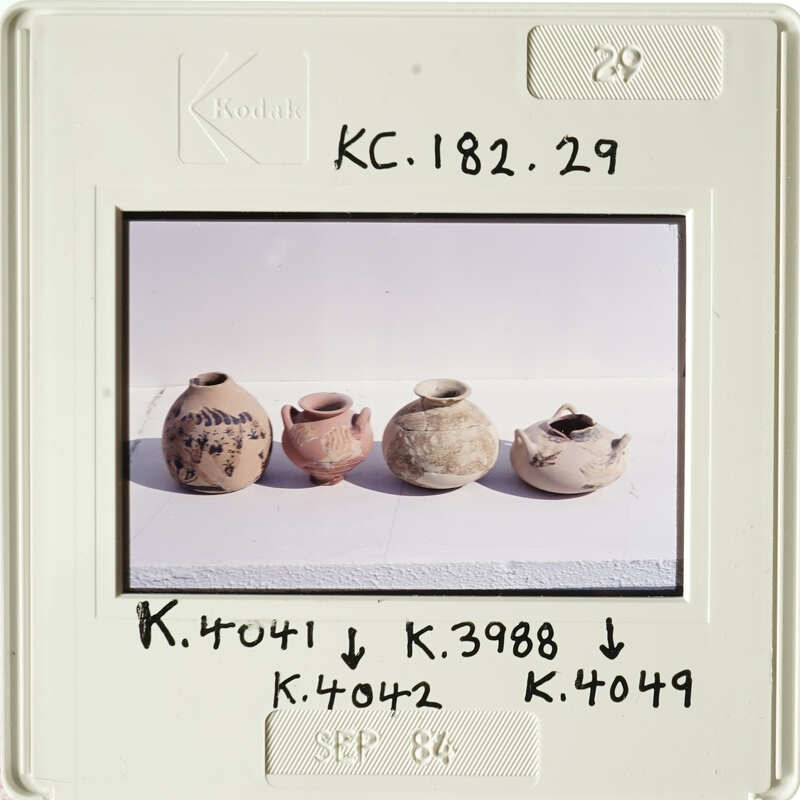 Old pottery displayed on a white surface, with labels and numbers written on the photo.