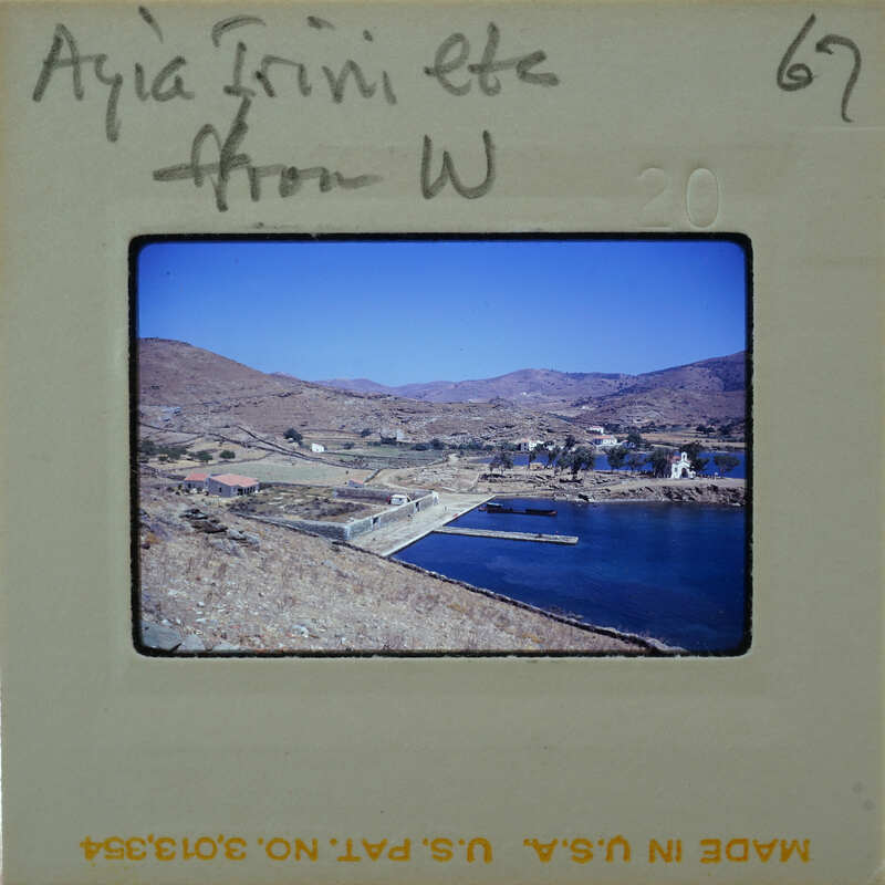A vintage photograph of a coastal landscape with mountains and houses, taken from an elevated perspective.