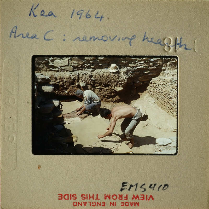 Two men working on an archaeological site, excavating and removing dirt with shovels.