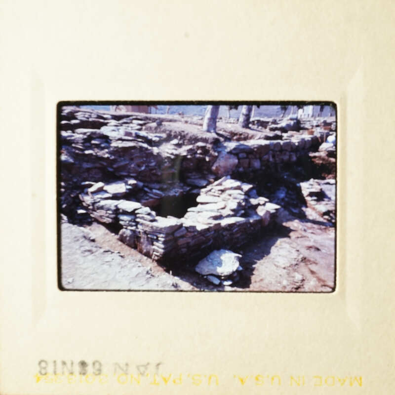 This is an image of a stone structure, possibly ruins, with a rocky landscape in the background.