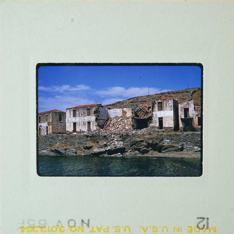 Abandoned buildings near a body of water, possibly an old fishing village.