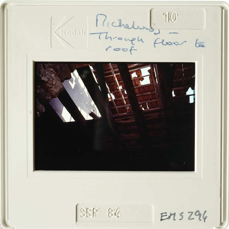 Old photograph showing interior with exposed wooden beams and rafters, possibly from an attic or roof space.