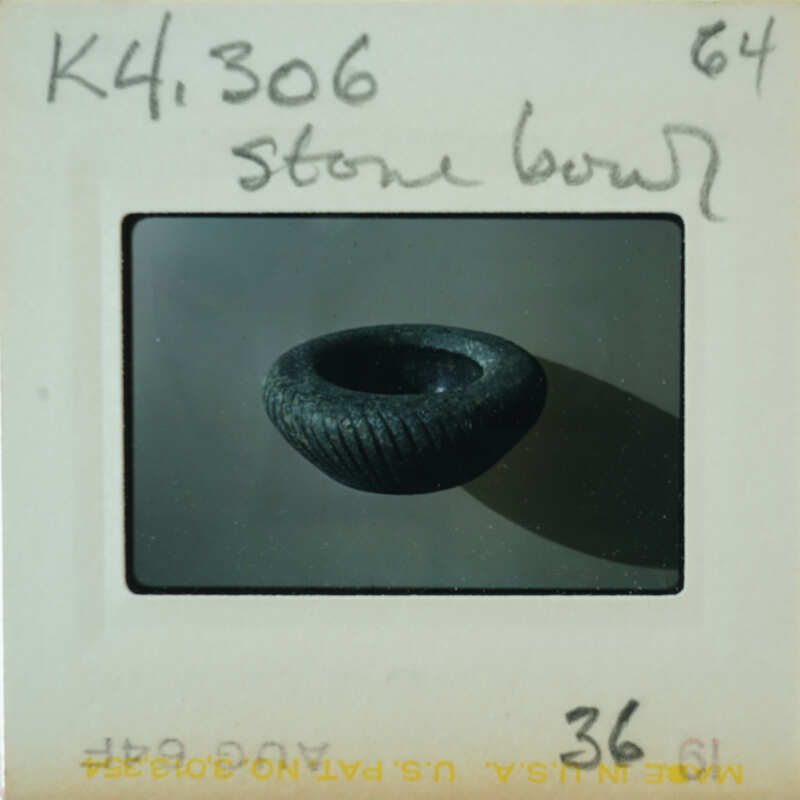 A stone bowl with a dark, rough texture and a slightly raised rim.