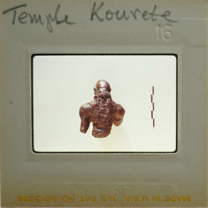 Small figurine of a man, possibly from ancient civilization, displayed on white background within a film strip frame.