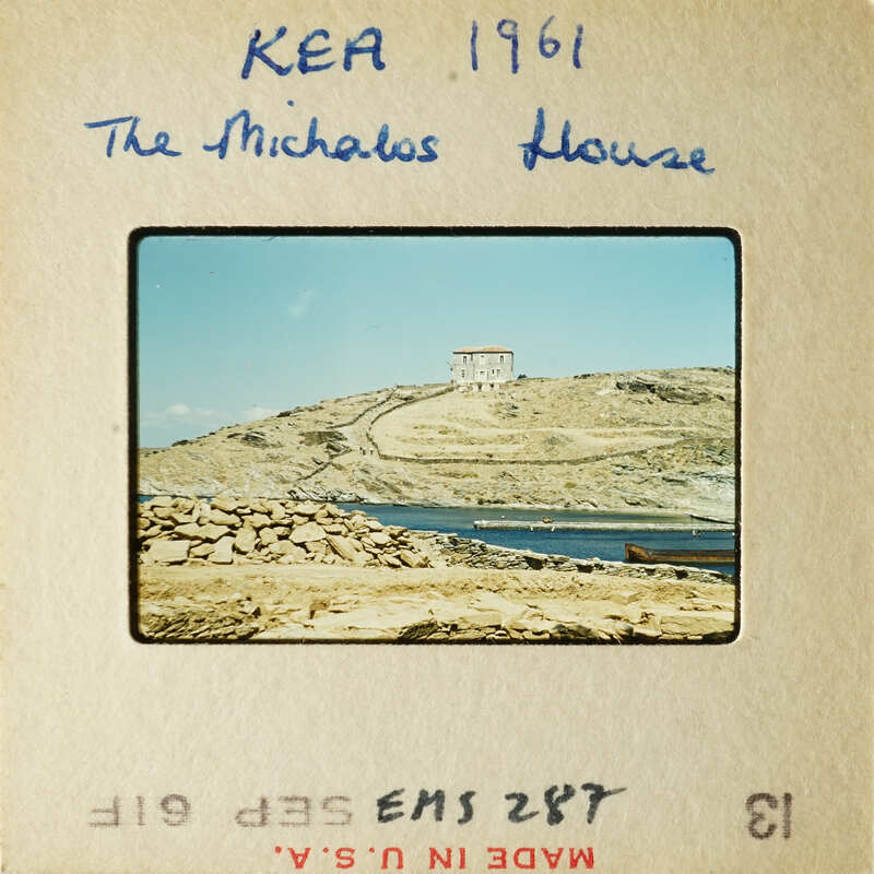A photograph of an island with a house on top, surrounded by water and rocks.