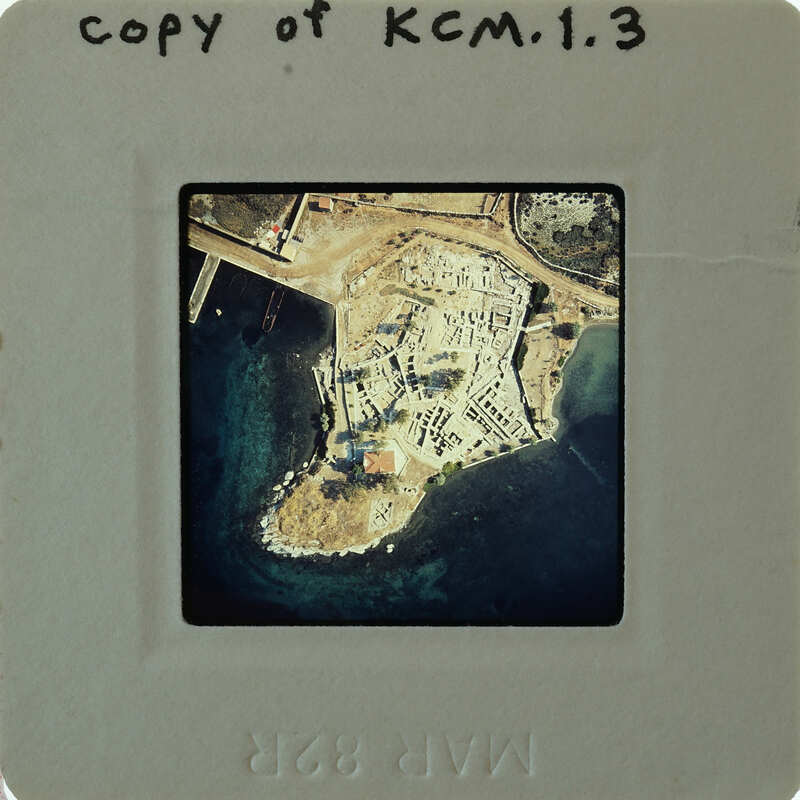 Aerial photograph of an island with a coastal road and buildings, printed on film.