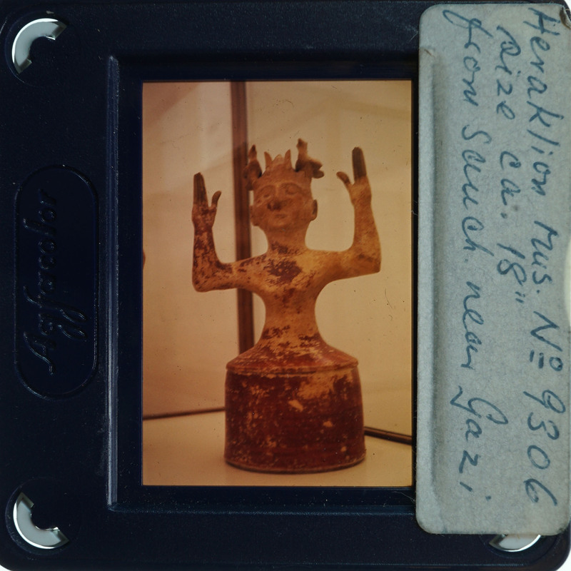 Old photograph with handwritten notes on a label, featuring an artifact of a figurine.