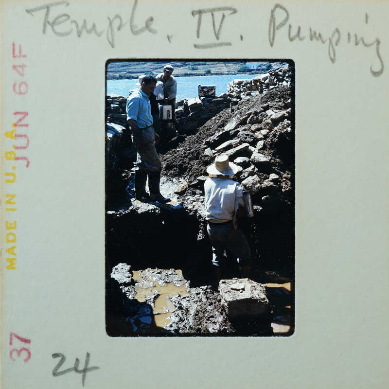 Three workers working on stone walls, partially under muddy water.