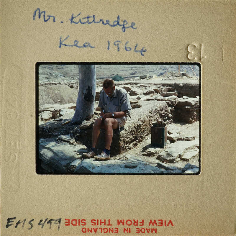 Man sitting on stone steps with ruins in background.