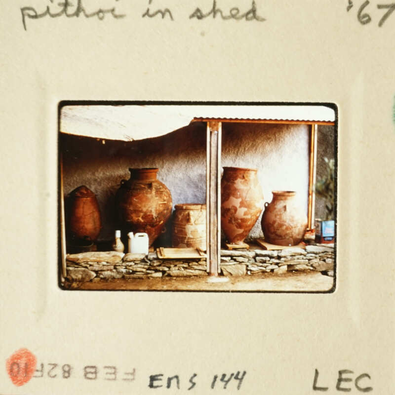 Vases on display inside a rustic structure with stone walls and wooden beams.