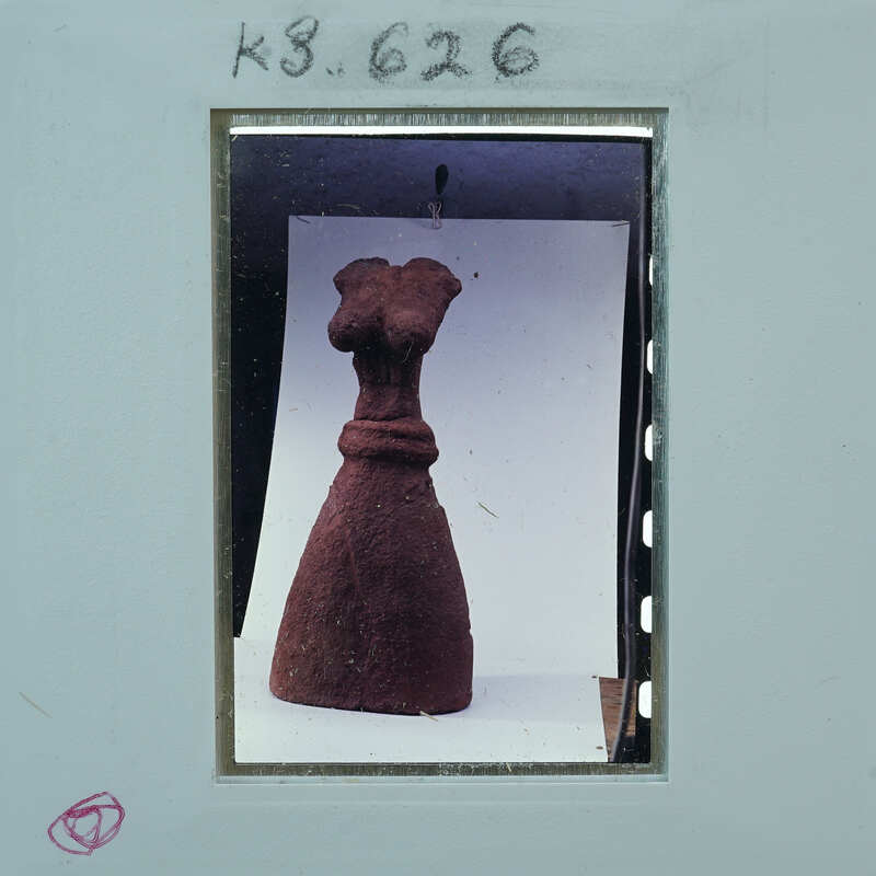 Ancient clay figurine of a woman on display with a label and number.