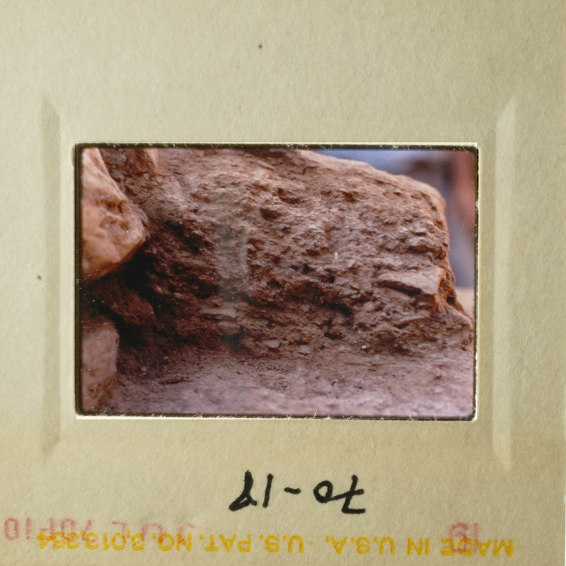 A rock formation with a small hole at the bottom, likely taken from an angle looking up.