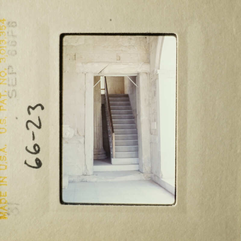 A black and white photograph capturing an interior staircase with a railing.