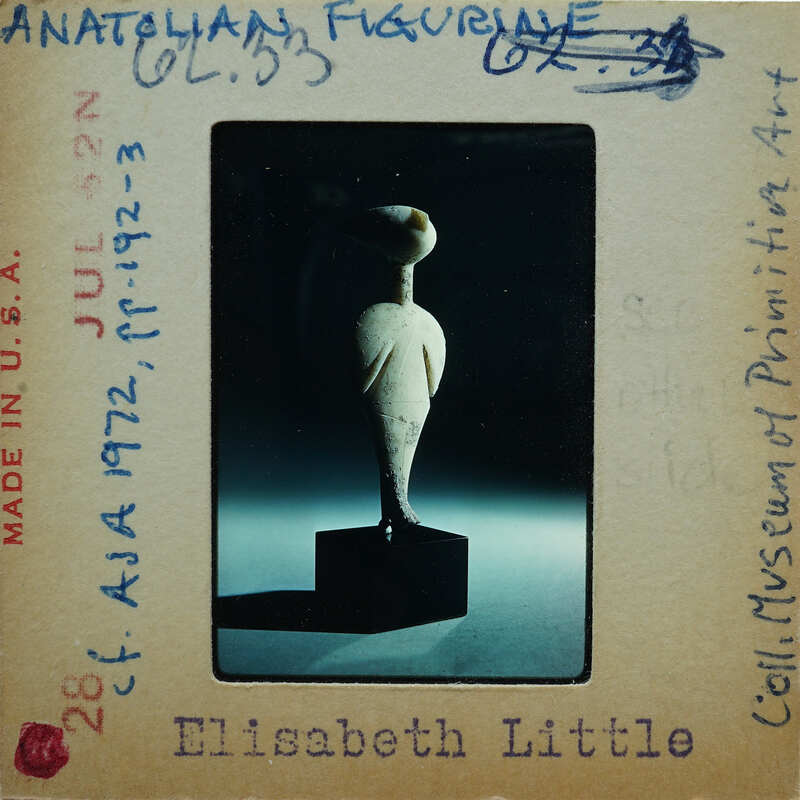 A photograph of a small sculpture with a vintage postcard background.