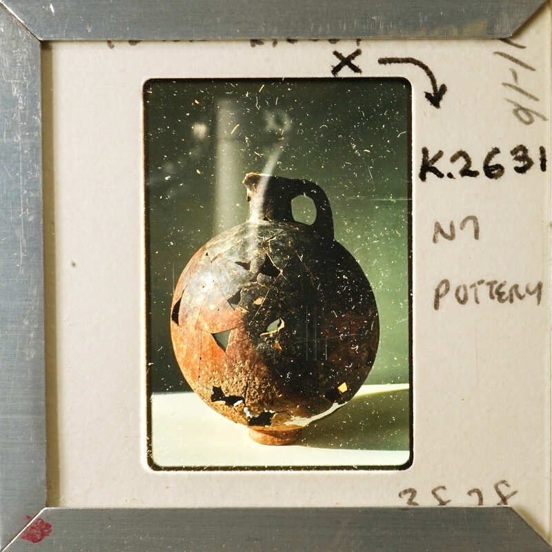 An old, weathered clay pot with a handle and an opening at the top.