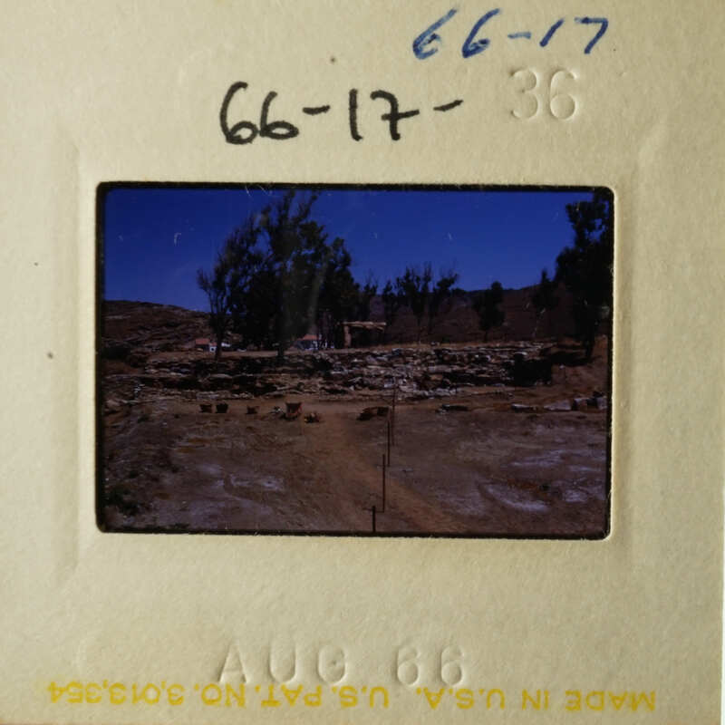 This is an image of a vintage photograph, possibly depicting a rural or desert landscape with a building and some trees.