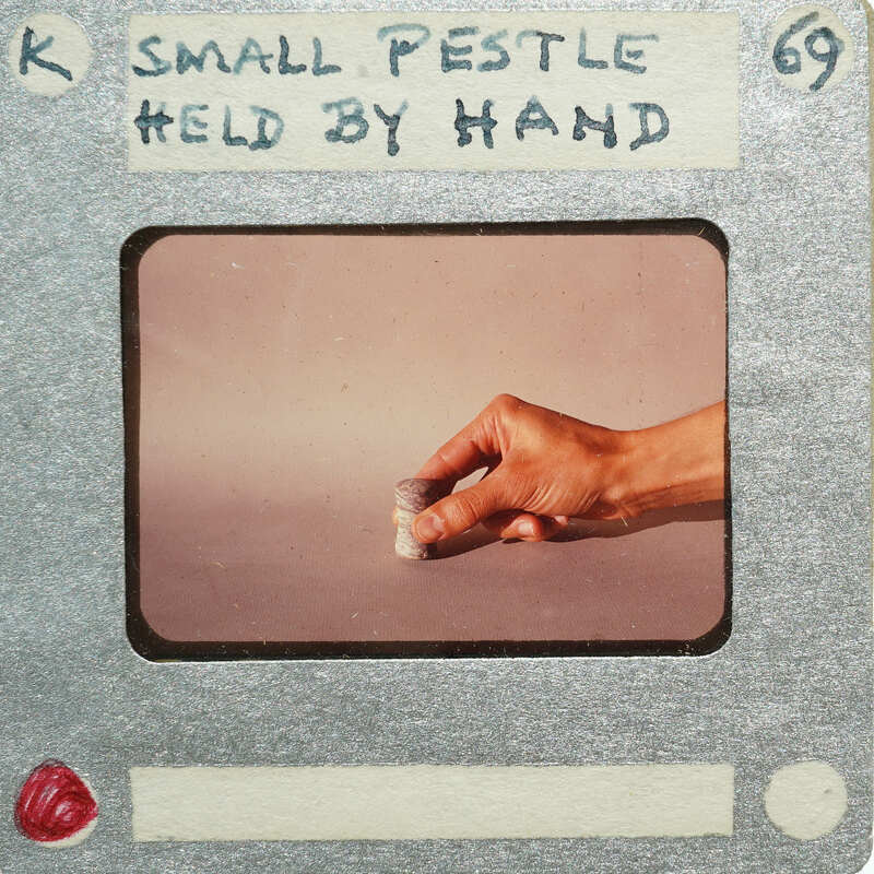 Hand holding small pestle and mortar.