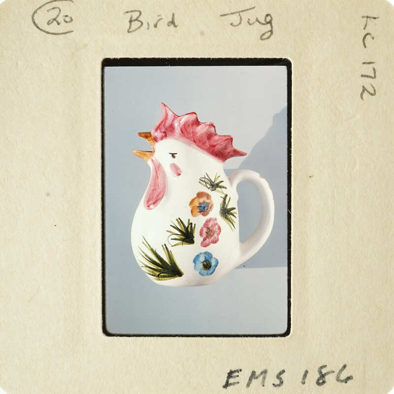 Decorative ceramic rooster mug with floral patterns on a blue background.