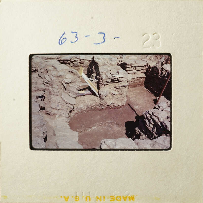 Ancient ruins with stone walls and a dirt floor, possibly from an archaeological site.