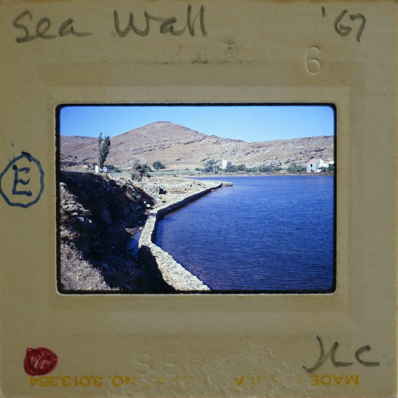 A vintage photograph of a scenic coastal landscape with a body of water and mountains, displayed on an old film strip.