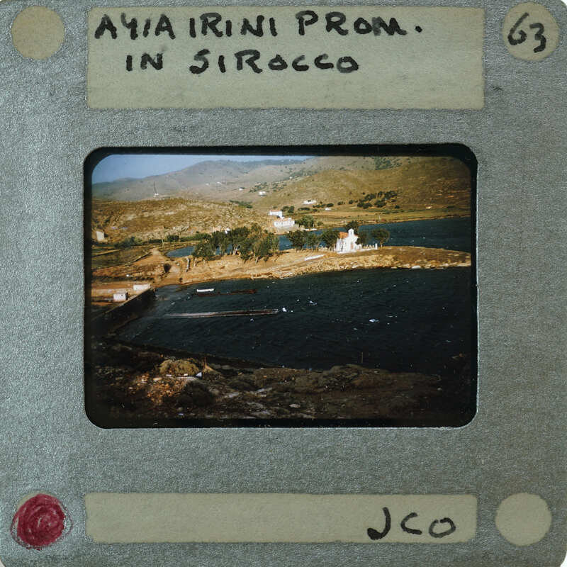 A vintage photo of a scenic landscape with mountains, water, and vegetation.
