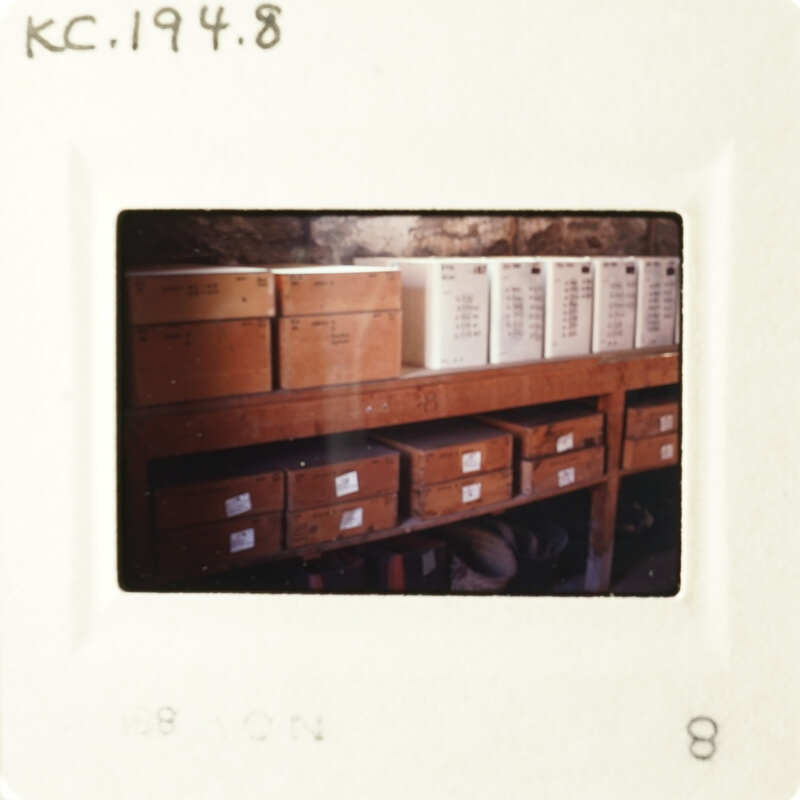 A photograph showing a room with boxes on shelves, taken from an angle where some of the boxes are obscured by the frame.