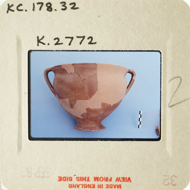 Ancient ceramic vase with visible cracks and missing pieces, displayed against a blue background.