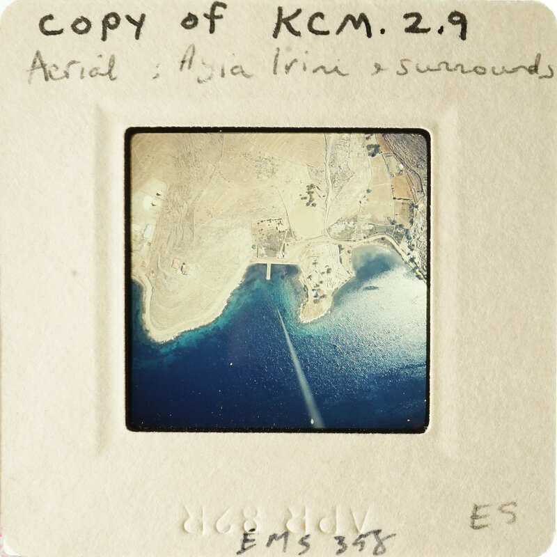 Aerial view of coastline with blue water and brown land, captured on an old photograph.