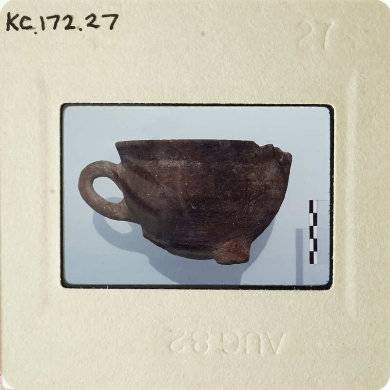 An antique ceramic cup with a handle, photographed on a white background and displayed within an object tag.