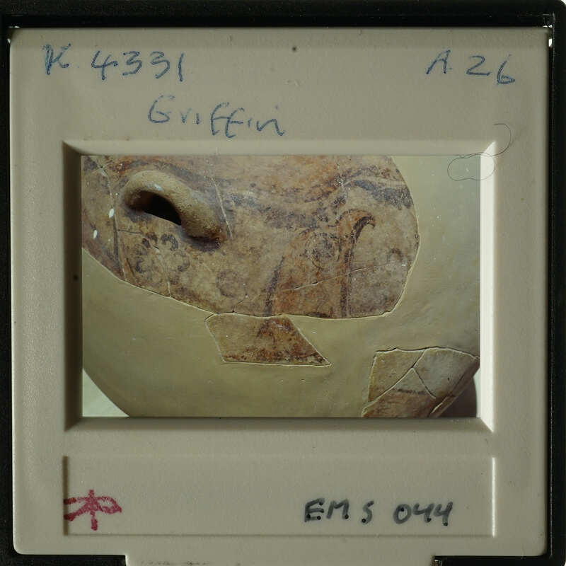 Ancient pottery with visible cracks and patterns, photographed against a blurred background.