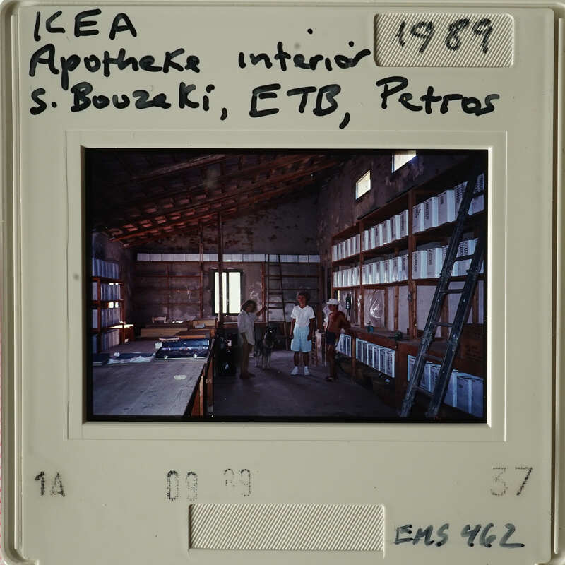 "Two people standing inside an industrial building with shelves and equipment."