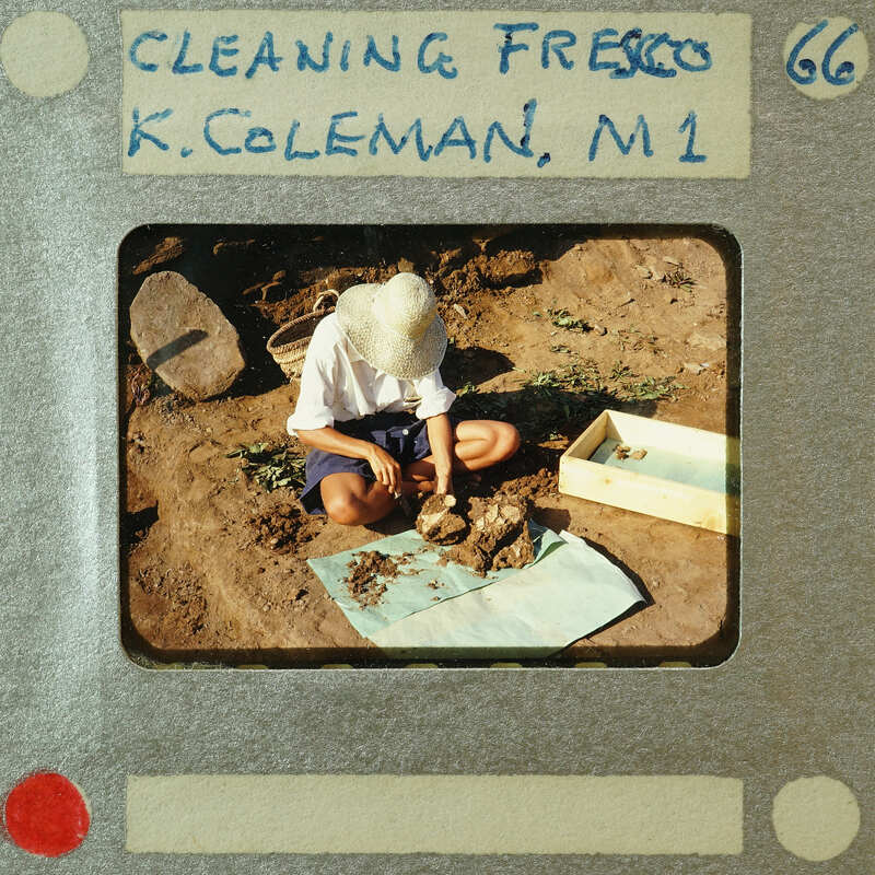 A person sitting on the ground, engaged with a pile of dirt and clay.