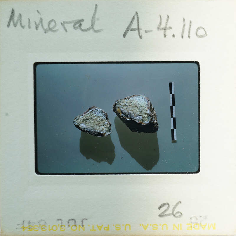 Two small rocks on a white background with measurement markings.