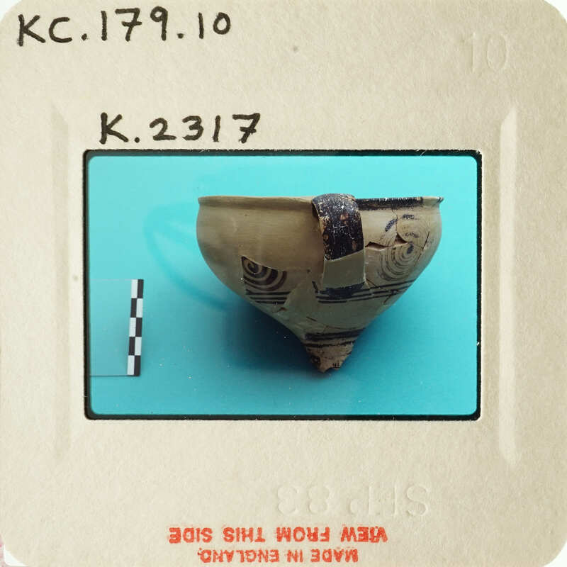 Ancient pottery artifact on display with visible markings and damage.