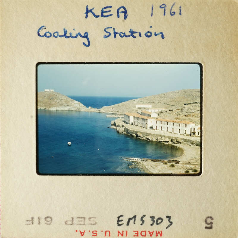 A photograph of an island harbor with buildings and boats, taken from a high vantage point.