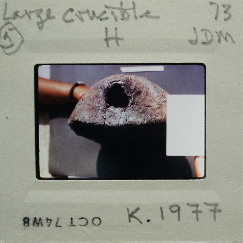 A photograph of a person holding a large, round, dark-colored object with a hole in the center.